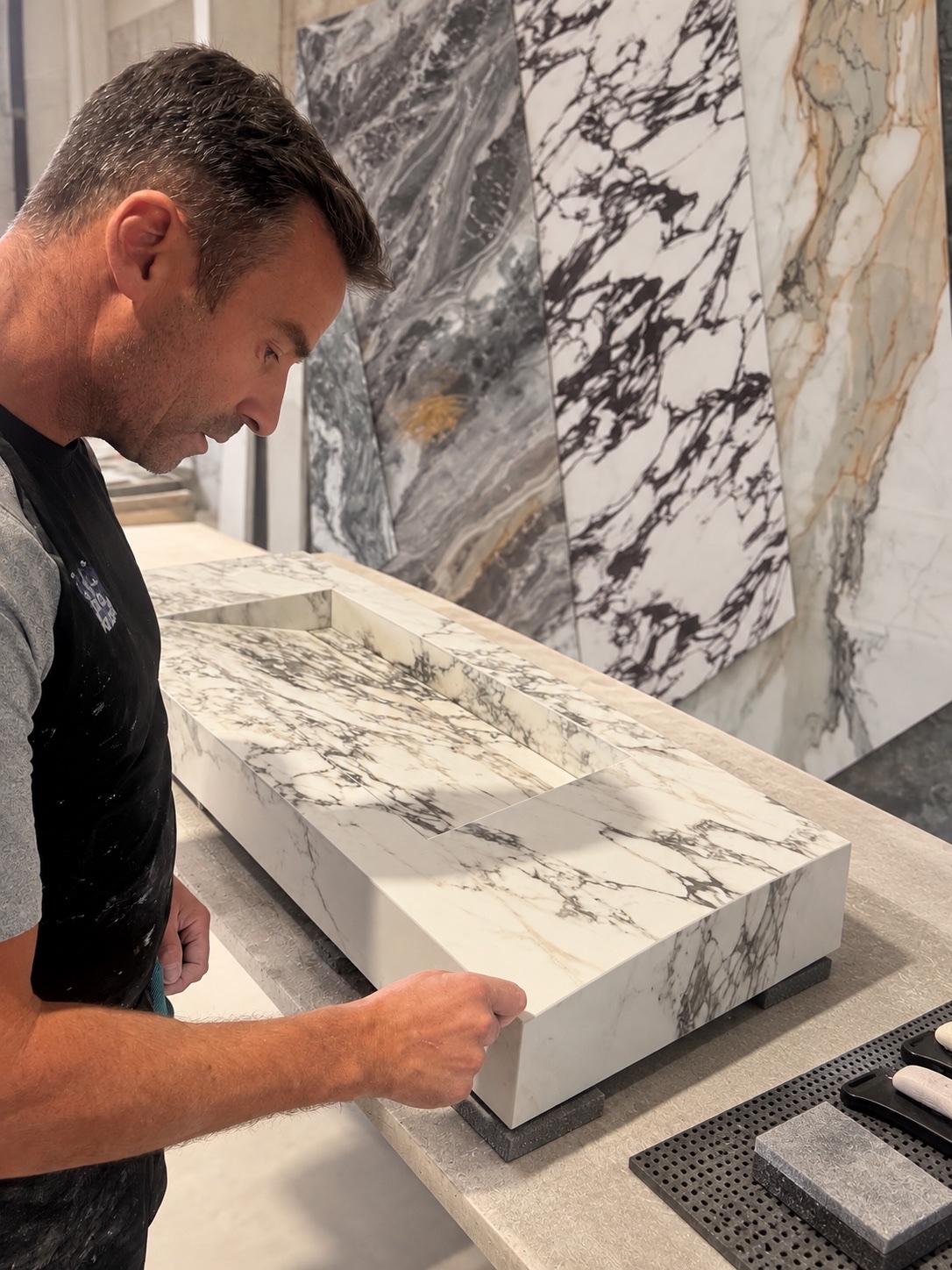 Our tiler checking the mitred edge of a hand-fabricated marble-effect porcelain basin in the workshop