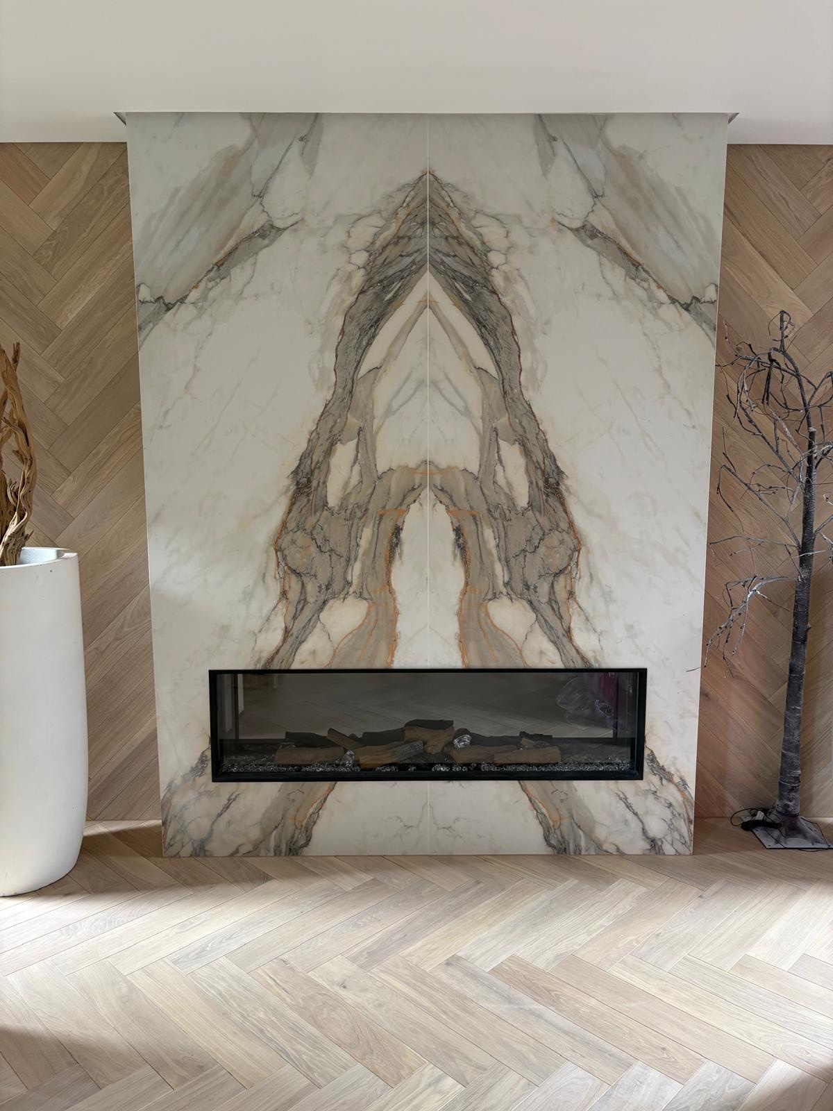 Floor-to-ceiling bookmatched marble-effect porcelain fireplace wall with a letterbox fire, set against herringbone oak panelling