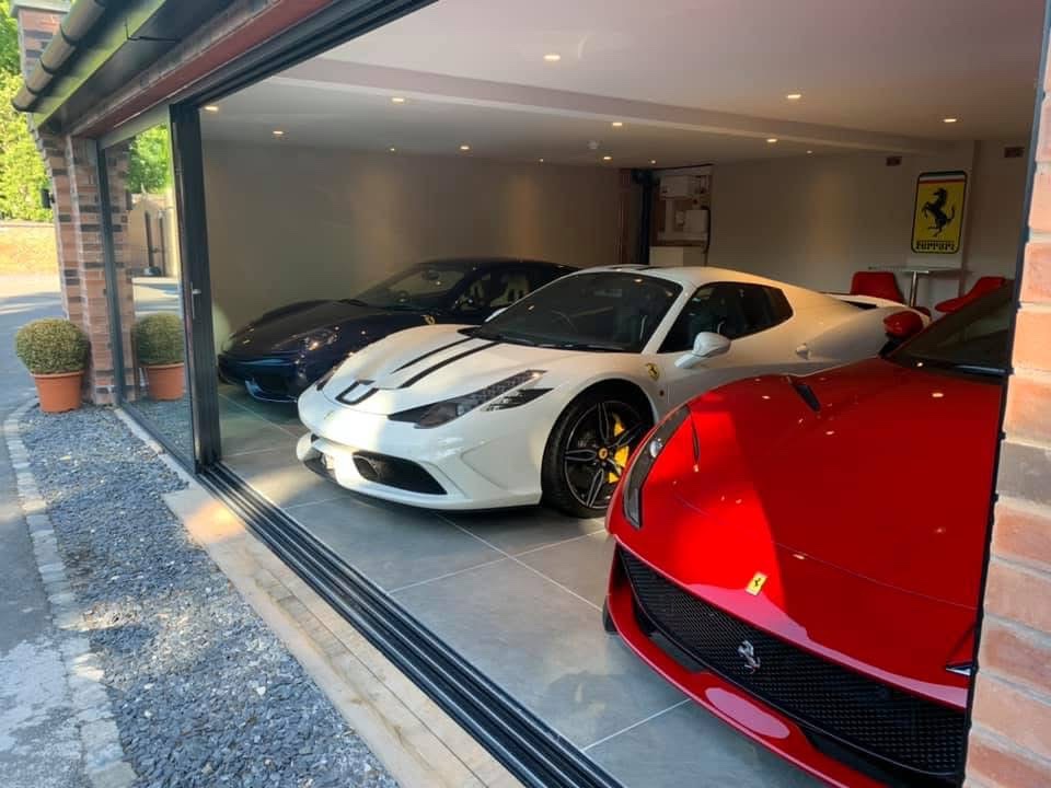 Luxury supercar garage with large-format grey porcelain floor tiles seen through open glazed doors