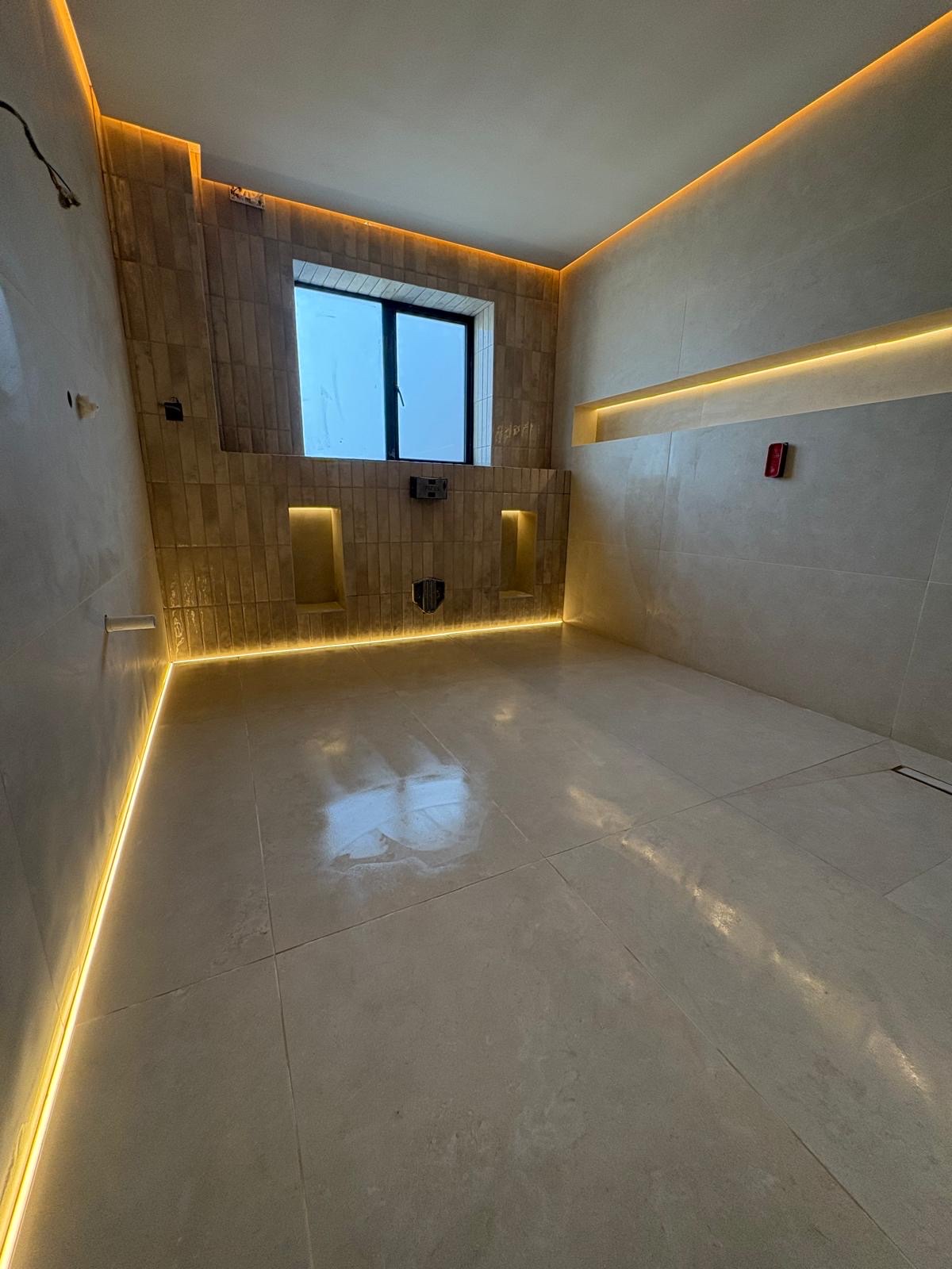 Wet room with large-format porcelain floor and walls, LED-lit recessed niches and a linear shower drain