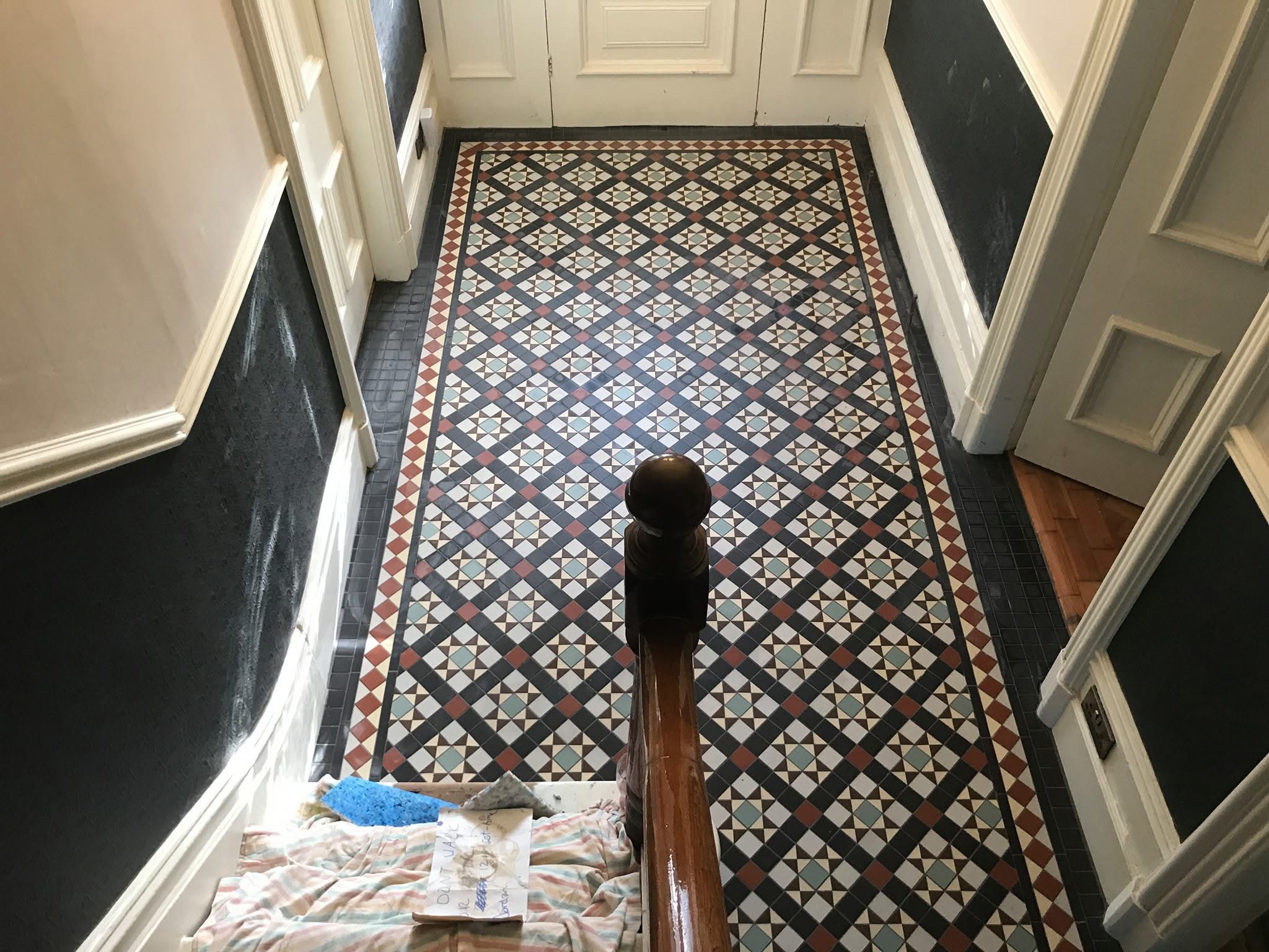 Victorian geometric mosaic hallway floor in black, white, red and blue with a red diamond border