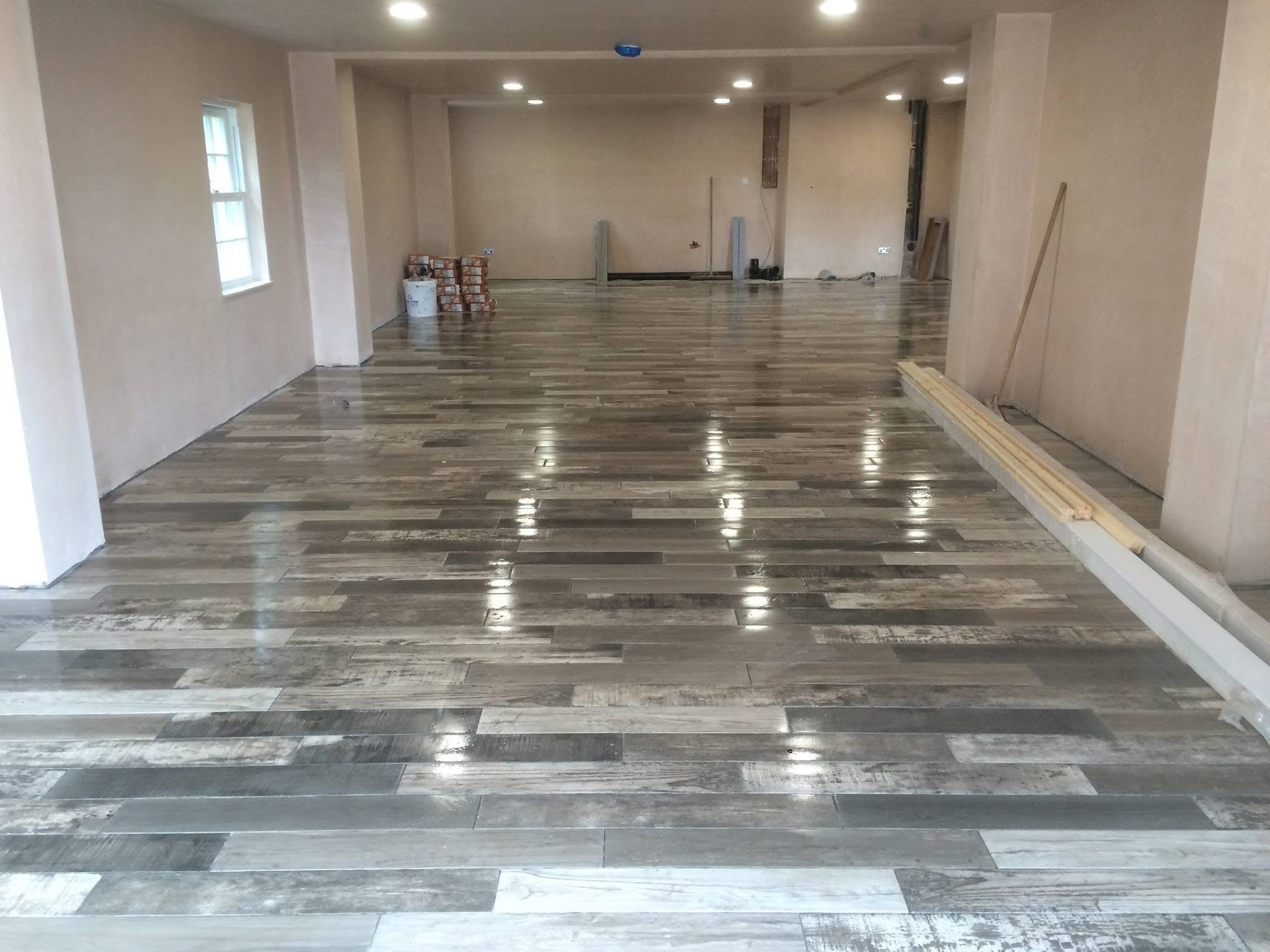 Large open-plan room with a freshly laid multi-tone wood-effect porcelain plank floor